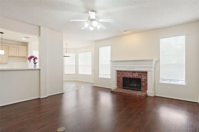 an empty room with wooden floor fireplace cabinet and windows