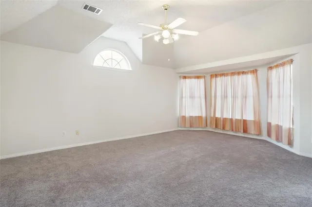 an empty room with windows and chandelier fan