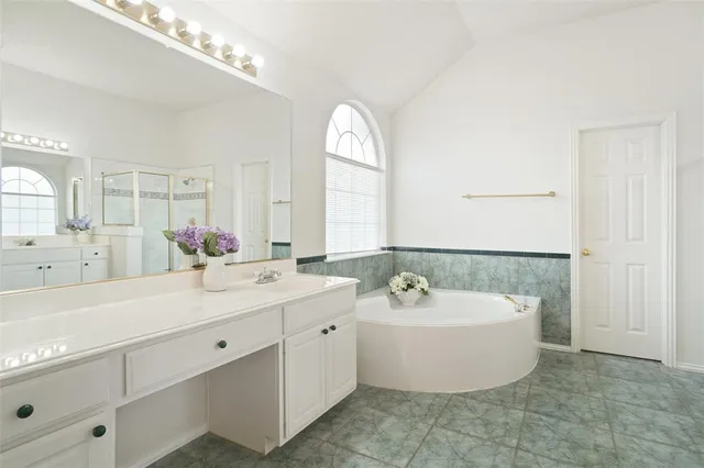 a spacious bathroom with a double vanity sink mirror and bathtub