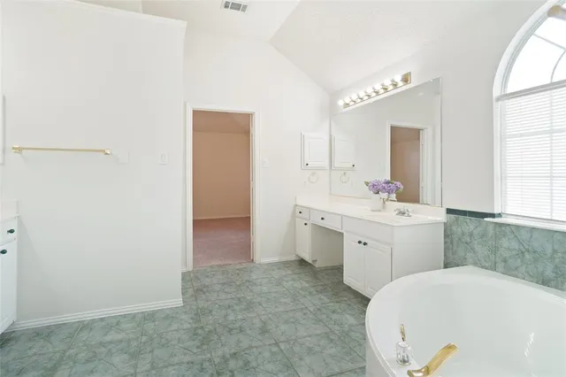 a spacious bathroom with a tub sink and mirror