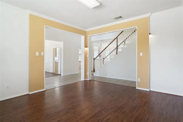 a view of an empty room with wooden floor and a bathroom
