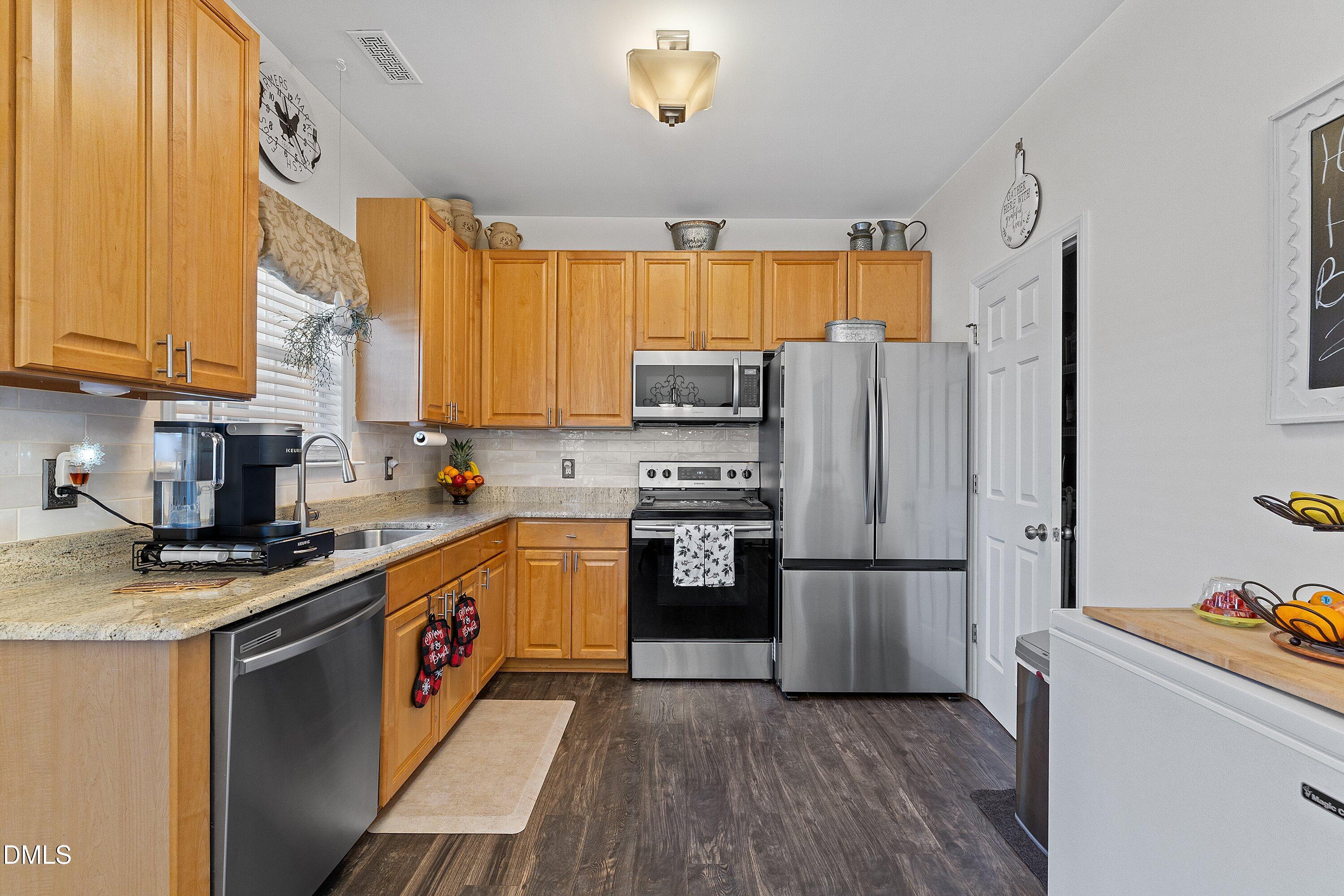 201 Dairy Road Clayton, NC 27520 - Photo 12 of 31 a kitchen with a refrigerator a microwave a sink and wooden floor