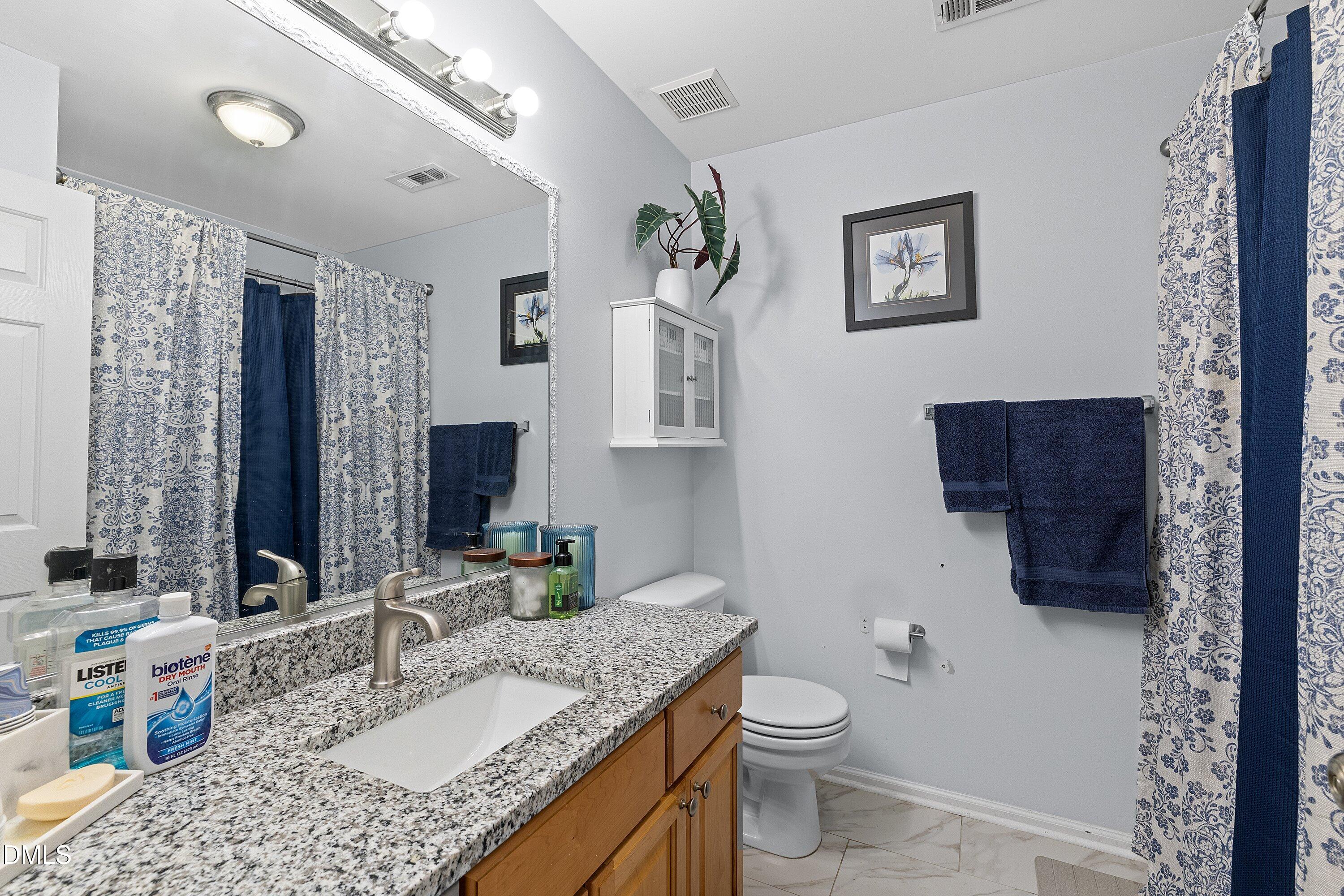 201 Dairy Road Clayton, NC 27520 - Photo 19 of 31 a bathroom with a granite countertop toilet a sink and a mirror