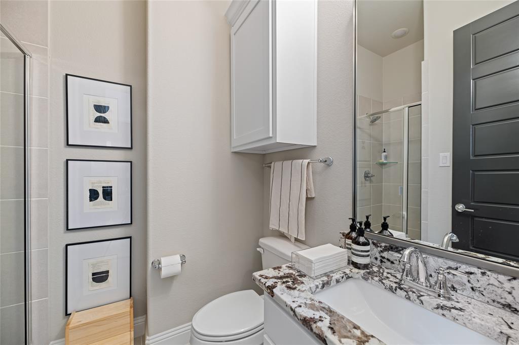 2262 Poppyvine Road Frisco, TX 75033 - Photo 15 of 40 Bathroom featuring a shower with a clear glass enclosure, a vanity with a white rectangular sink and granite countertop, and a white cabinet for storage