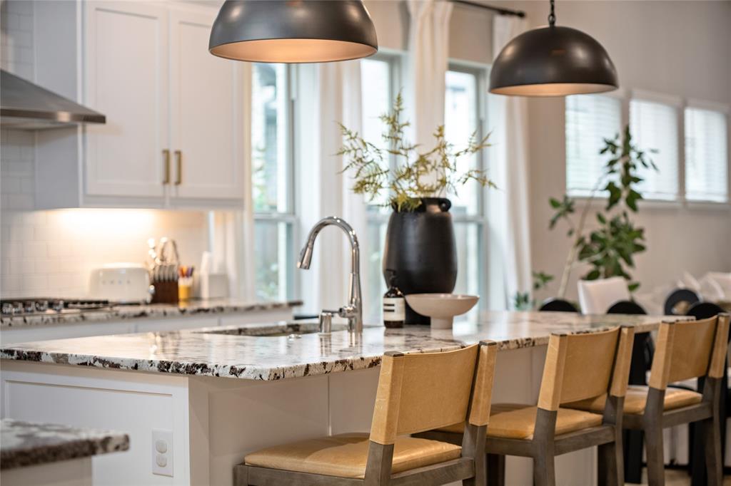 2262 Poppyvine Road Frisco, TX 75033 - Photo 24 of 40 The kitchen features an island with a polished stone countertop, a sink with a chrome faucet, and seating for four