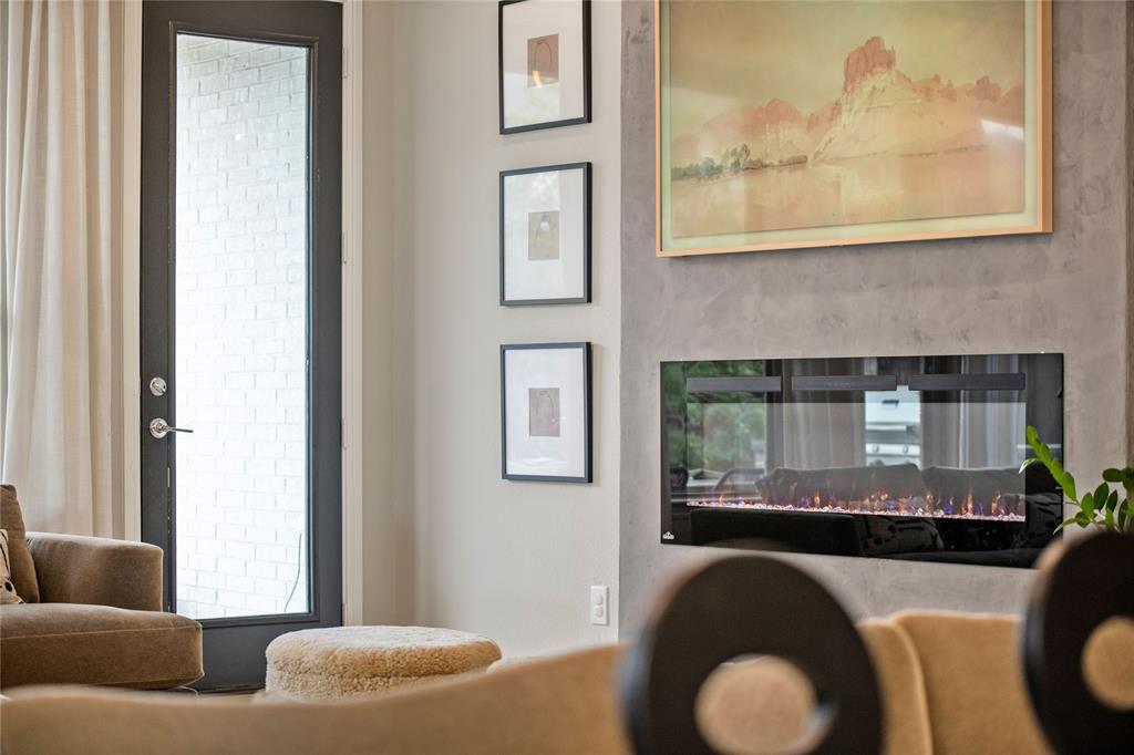 2262 Poppyvine Road Frisco, TX 75033 - Photo 25 of 40 This inviting space features a modern fireplace with a glass front, set into a textured wall, and a full-light exterior door with a dark frame, providing natural light