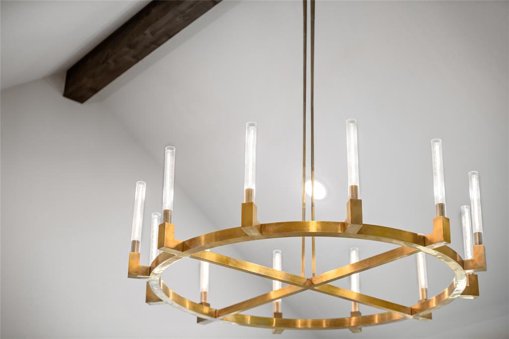 2262 Poppyvine Road Frisco, TX 75033 - Photo 27 of 40 The property features a contemporary chandelier with a brass finish and exposed light sources, complemented by a prominent dark wooden beam against a light-colored ceiling