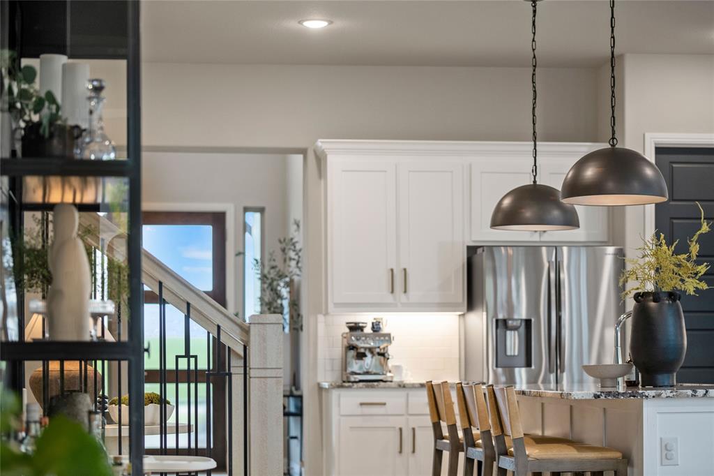 2262 Poppyvine Road Frisco, TX 75033 - Photo 28 of 40 This kitchen features white cabinetry, stainless steel appliances, and two pendant lights above a granite countertop