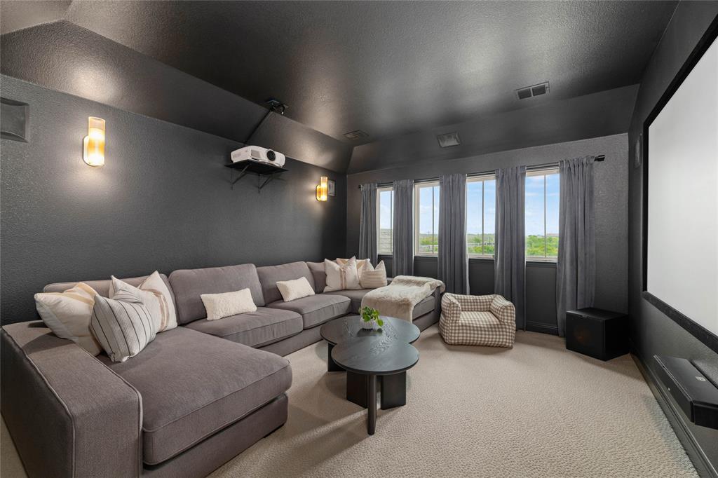 2262 Poppyvine Road Frisco, TX 75033 - Photo 29 of 40 This media room features a large projection screen, a ceiling-mounted projector, four windows with drapes, and sconce lighting