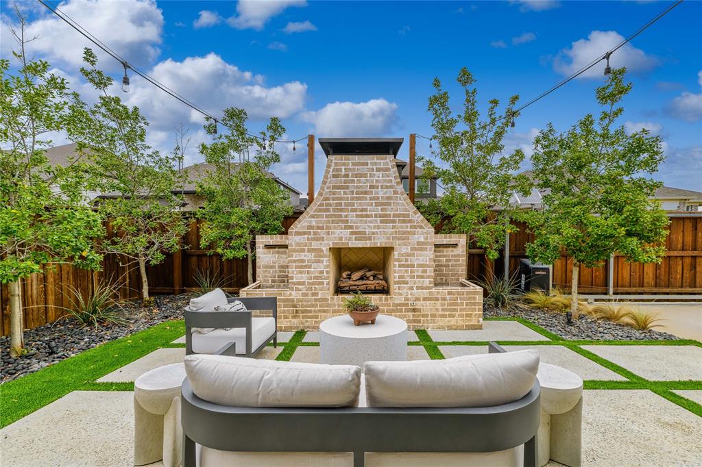 2262 Poppyvine Road Frisco, TX 75033 - Photo 37 of 40 The property features a patio with a brick fireplace, string lighting, and a combination of concrete pavers and grass