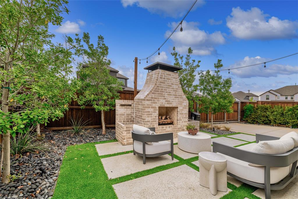 2262 Poppyvine Road Frisco, TX 75033 - Photo 38 of 40 The property includes a landscaped yard featuring a brick outdoor fireplace, string lighting, paved patio sections, and a lawn area