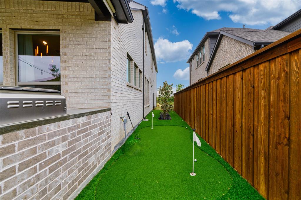 2262 Poppyvine Road Frisco, TX 75033 - Photo 39 of 40 This property features a synthetic turf putting green with two holes, alongside a wooden fence