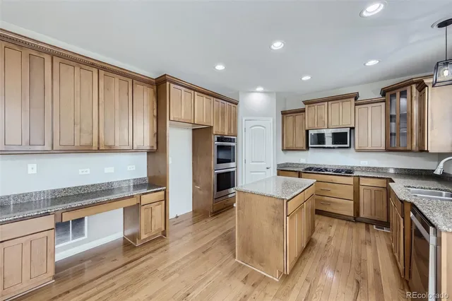 a kitchen with stainless steel appliances granite countertop a stove top oven a sink dishwasher a refrigerator and cabinets with wooden floor