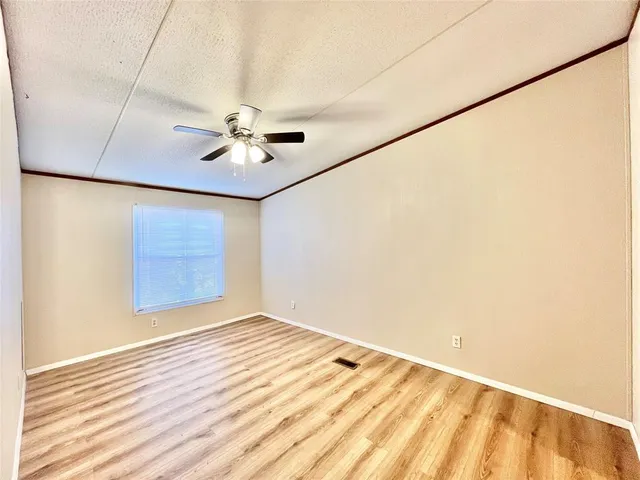 an empty room with a ceiling fan and wooden floor