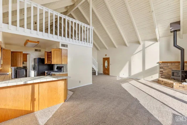 a view of a kitchen with kitchen island stainless steel appliances wooden floor and furniture
