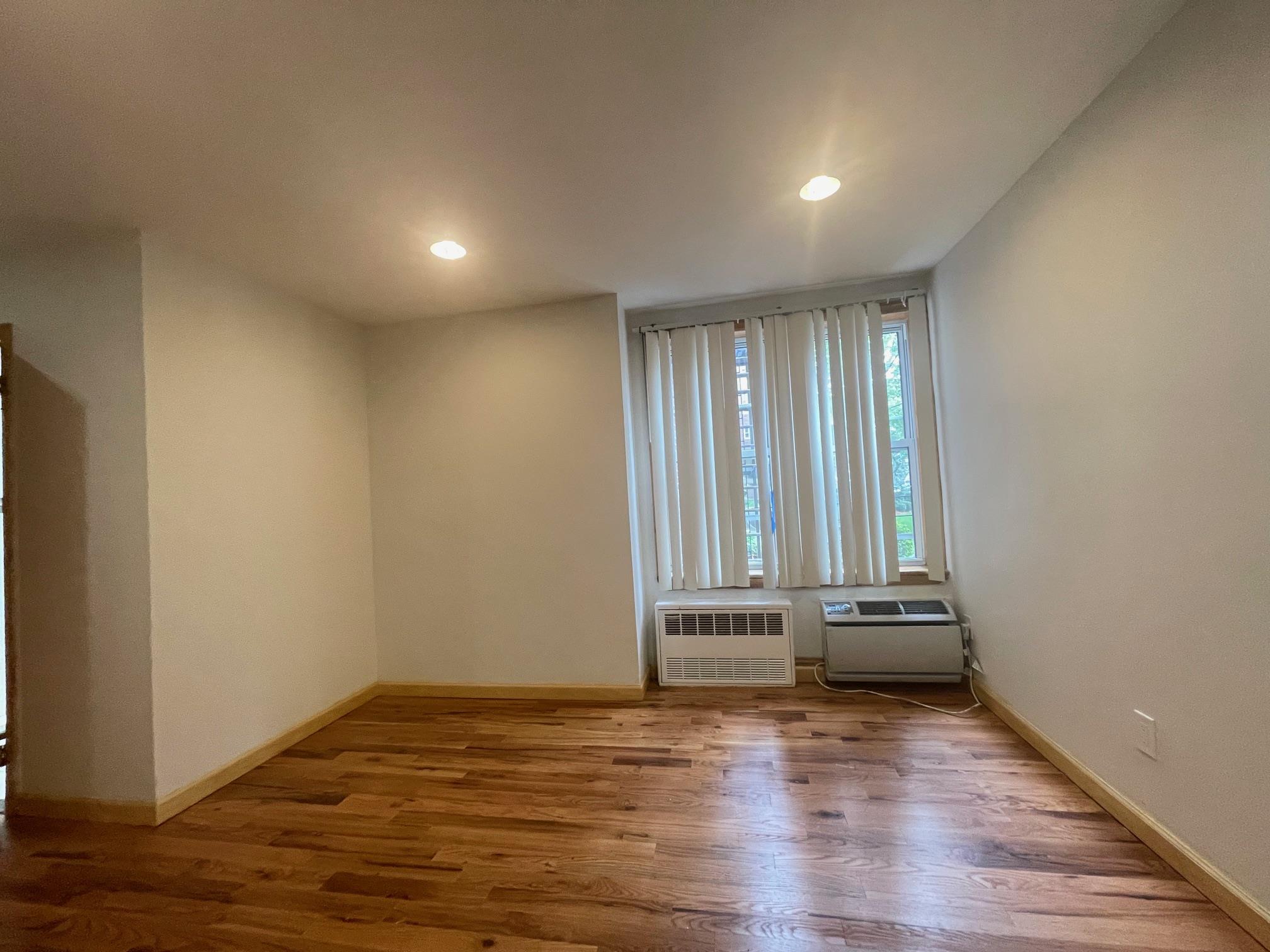 59-30 108th Street, Unit 2JJ Queens, NY 11368 - Photo 5 of 15 Empty room featuring an AC wall unit, wood finished floors, and recessed lighting