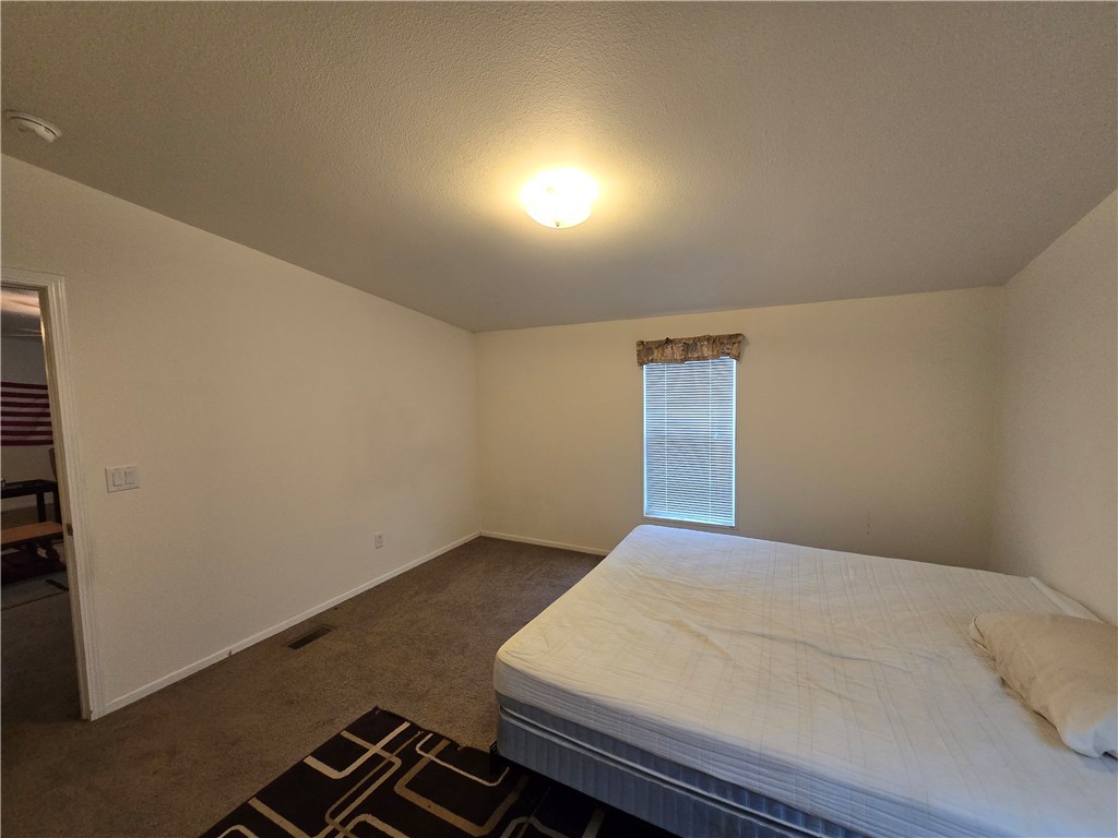 3689 North Avra Road Golden Valley, AZ 86413 - Photo 14 of 32 Unfurnished bedroom featuring dark carpet and a textured ceiling