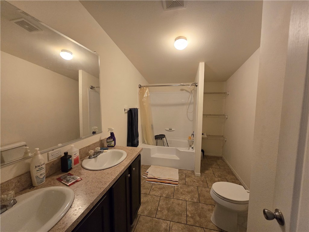 3689 North Avra Road Golden Valley, AZ 86413 - Photo 15 of 32 Bathroom featuring shower / bath combo with shower curtain, double vanity, and dark tile patterned floors