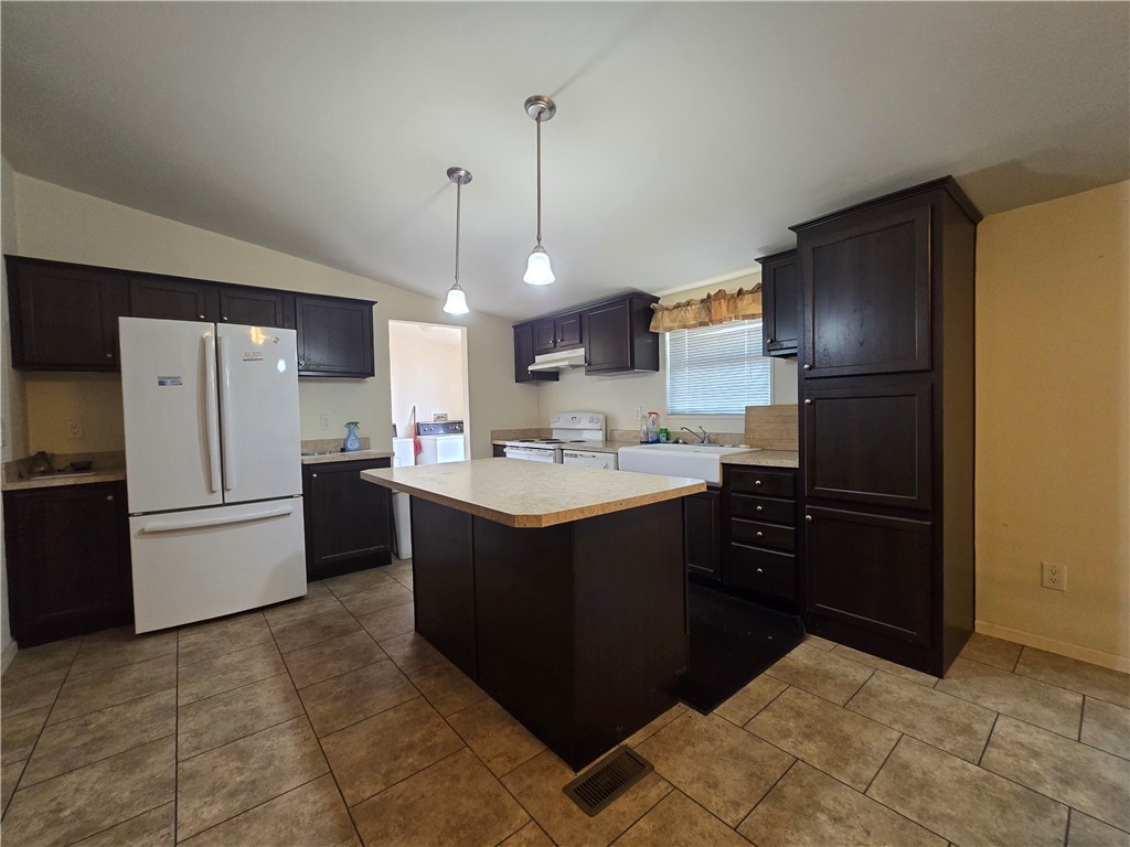 3689 North Avra Road Golden Valley, AZ 86413 - Photo 3 of 32 Kitchen featuring white appliances, light countertops, pendant lighting, vaulted ceiling, and a kitchen island