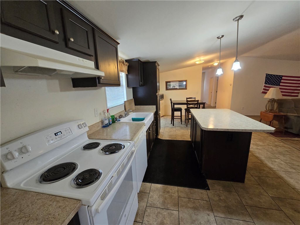 3689 North Avra Road Golden Valley, AZ 86413 - Photo 32 of 32 Kitchen featuring white appliances, under cabinet range hood, open floor plan, light countertops, and light tile patterned floors