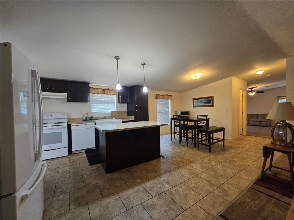 3689 North Avra Road Golden Valley, AZ 86413 - Photo 7 of 32 Kitchen featuring white appliances, light countertops, dark cabinetry, decorative light fixtures, and a center island