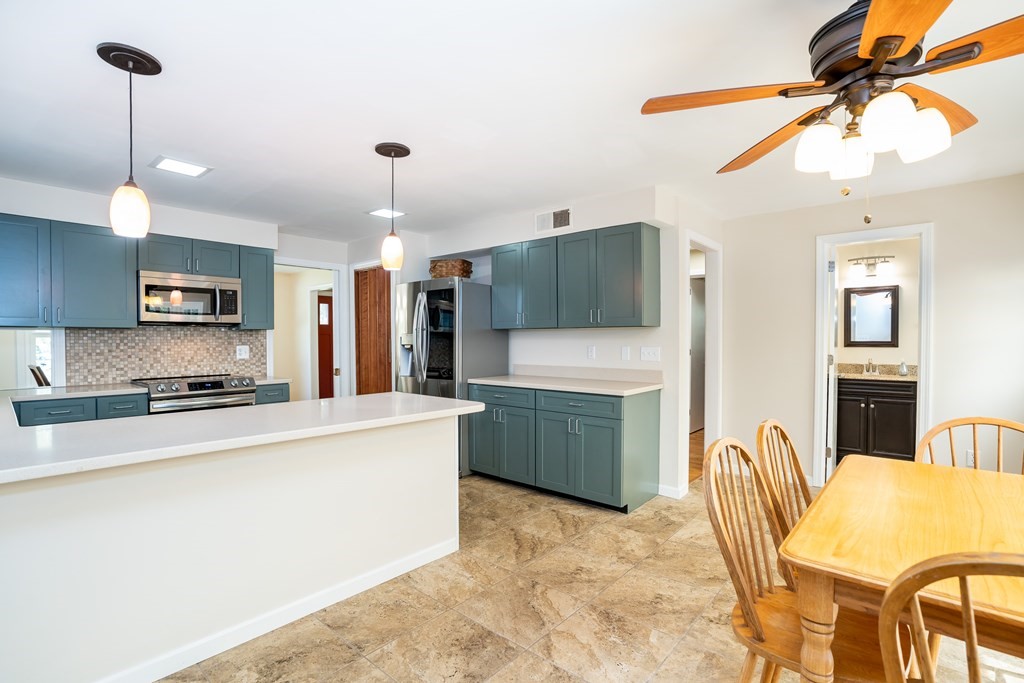 19 Pebble Ridge Road Amherst, MA 01002 - Photo 20 of 42 a kitchen with stainless steel appliances granite countertop a stove top oven a refrigerator a sink dishwasher a dining table and chairs with wooden floor