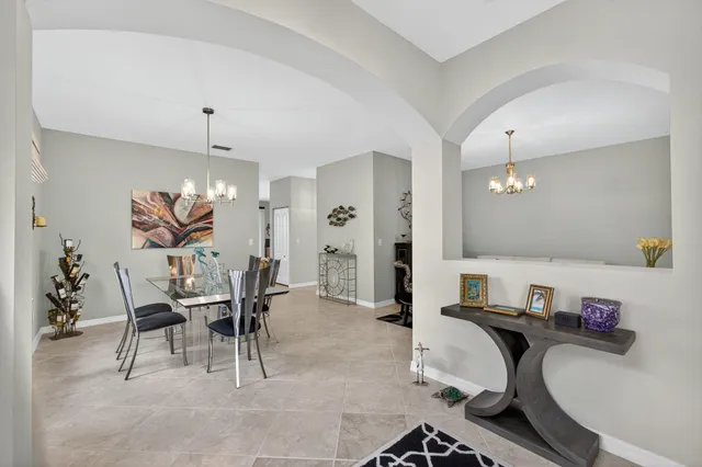 a view of a dining room and livingroom with furniture wooden floor a rug a painting and a chandelier