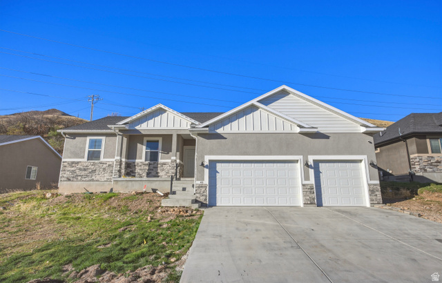 45 Memory Lane Tooele, UT 84074 - Photo 1 of 30 Craftsman-style home with stone siding, an attached garage, concrete driveway, covered porch, and board and batten siding