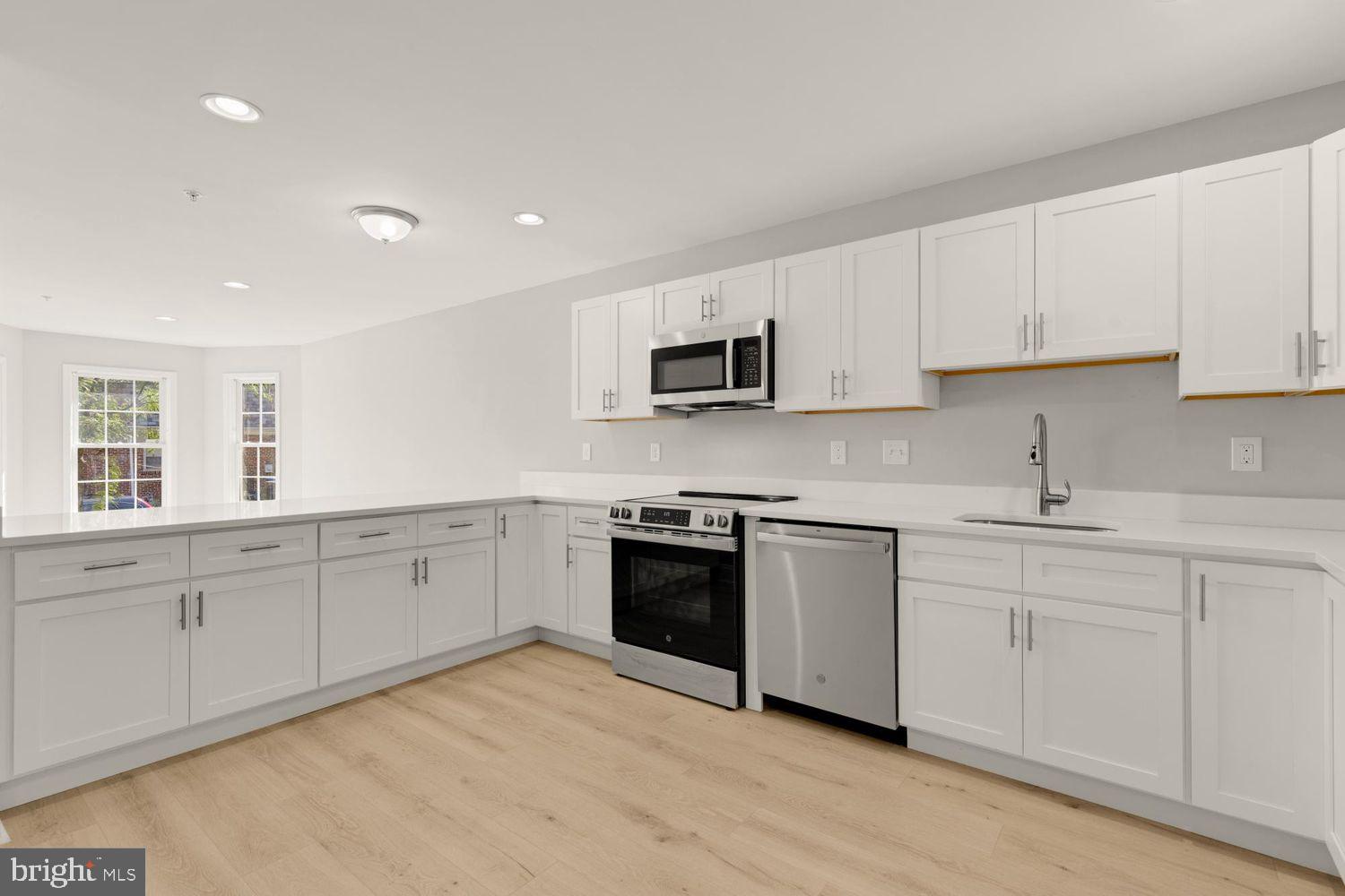 1755 W Street Southeast, Unit A Washington, DC 20020 - Photo 16 of 35 a kitchen with stainless steel appliances granite countertop a stove top oven a sink and dishwasher with wooden floor