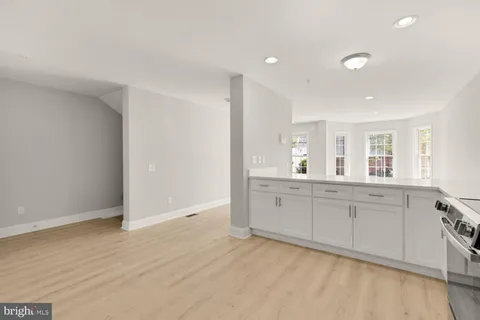 a large white kitchen with granite countertop a sink and dishwasher with wooden floor