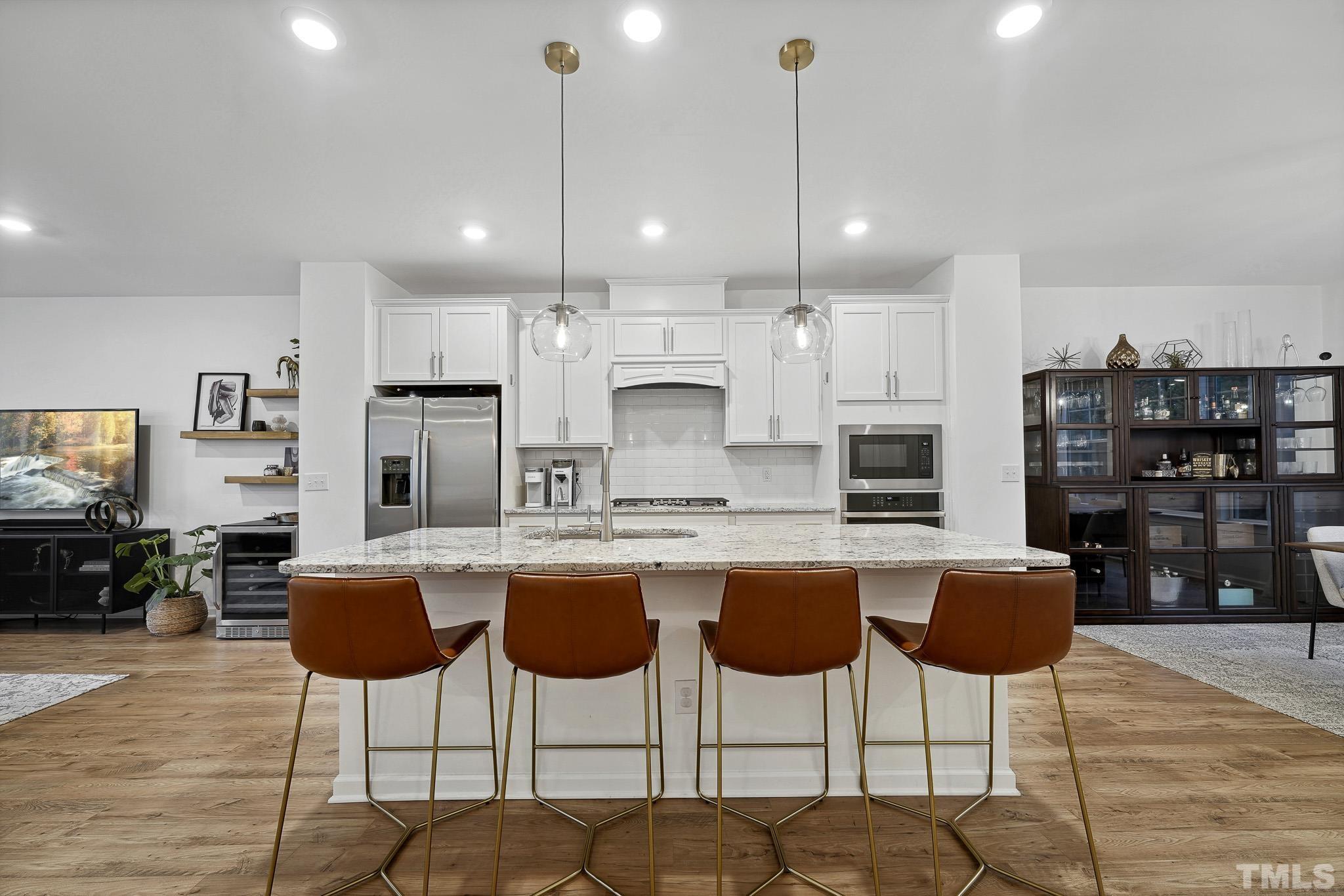 3251 Lynn Road Raleigh, NC 27613 - Photo 14 of 29 a kitchen with stainless steel appliances kitchen island granite countertop a dining table chairs and white cabinets