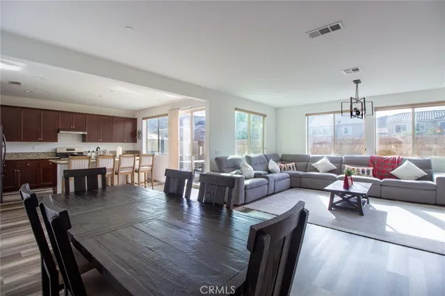 a living room with lots of furniture kitchen view and a large window