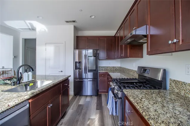 a kitchen with stainless steel appliances granite countertop a sink stove and refrigerator