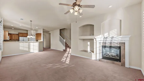 a view of a livingroom with a chandelier fan and windows