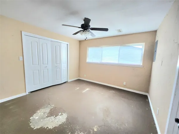 an empty room with a ceiling fan and a window