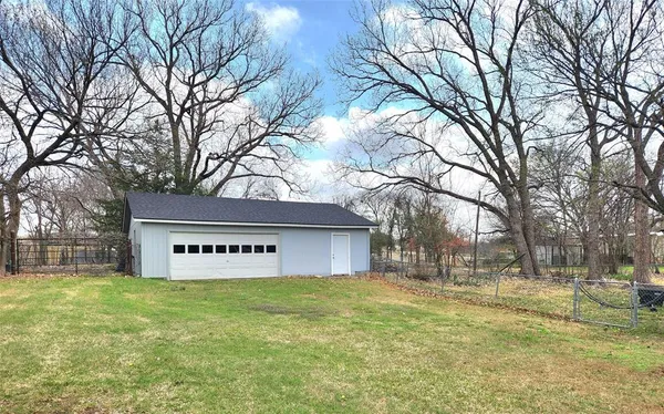 a sign that is sitting in front of a house with large trees