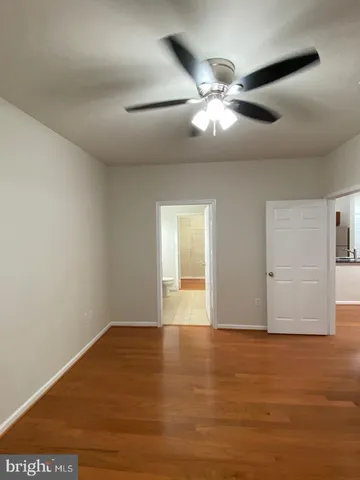 an empty room with wooden floor and fan