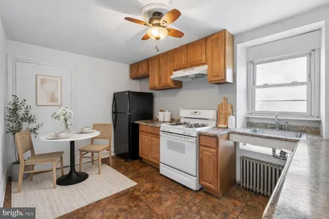 a kitchen with a sink dishwasher a stove a dining table and chairs with wooden floor