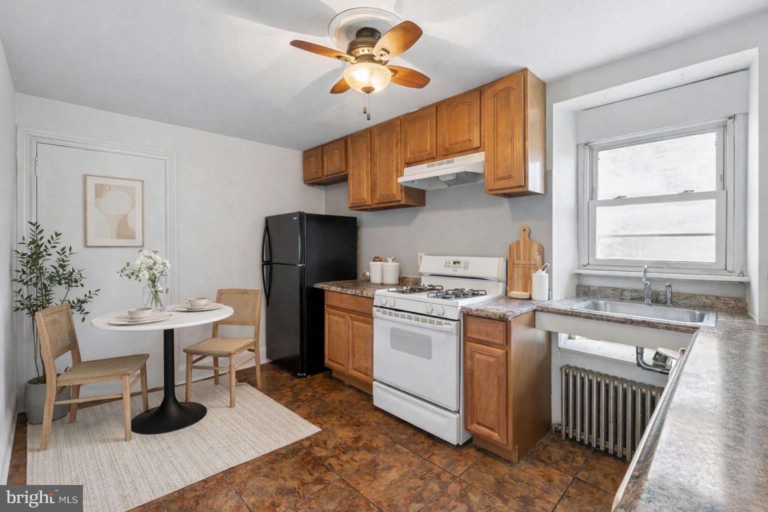 439 Lemonte Street Philadelphia, PA 19128 - Photo 6 of 42 a kitchen with a sink dishwasher a stove a dining table and chairs with wooden floor
