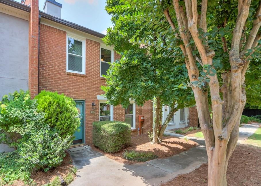a tree in front of a house with potted plants