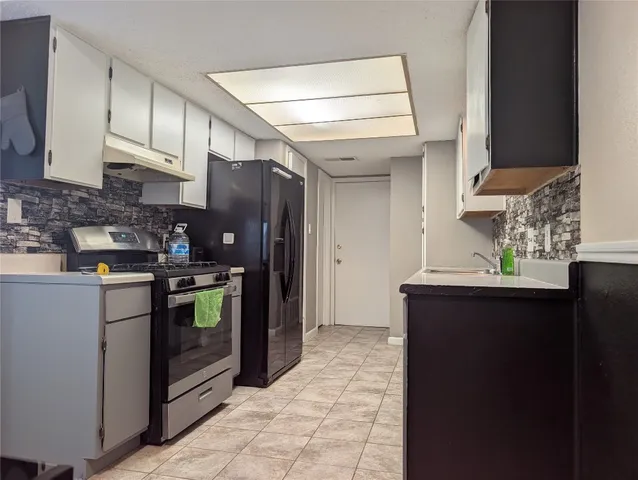 a kitchen with stainless steel appliances granite countertop a refrigerator a sink and wooden cabinets