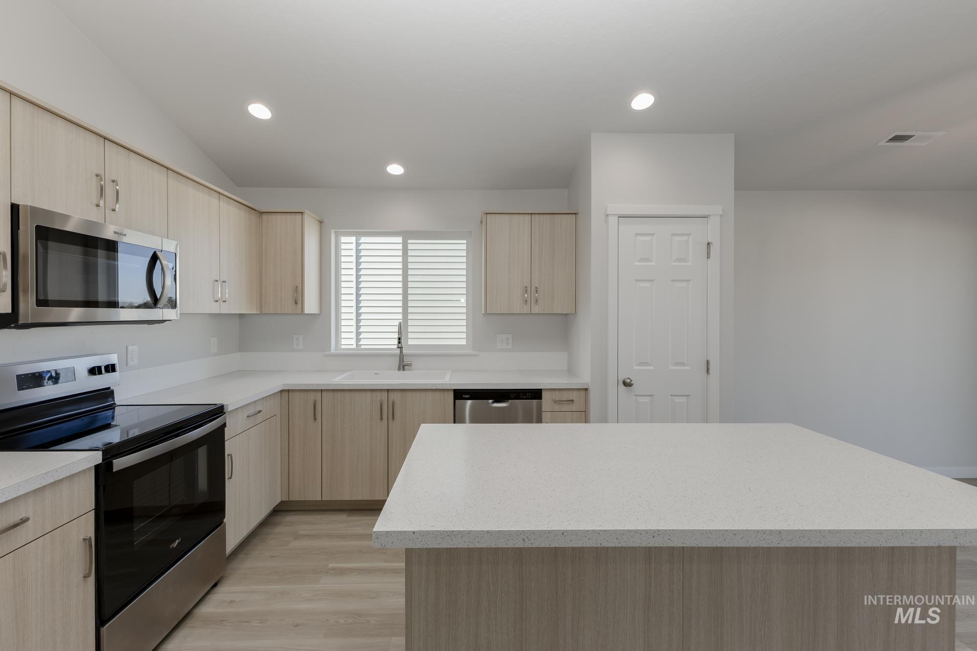 13337 Scrape Street Caldwell, ID 83607 - Photo 7 of 19 Kitchen featuring wood-finish cabinetry, stainless steel appliances, light-toned countertops, a central island, and recessed lighting