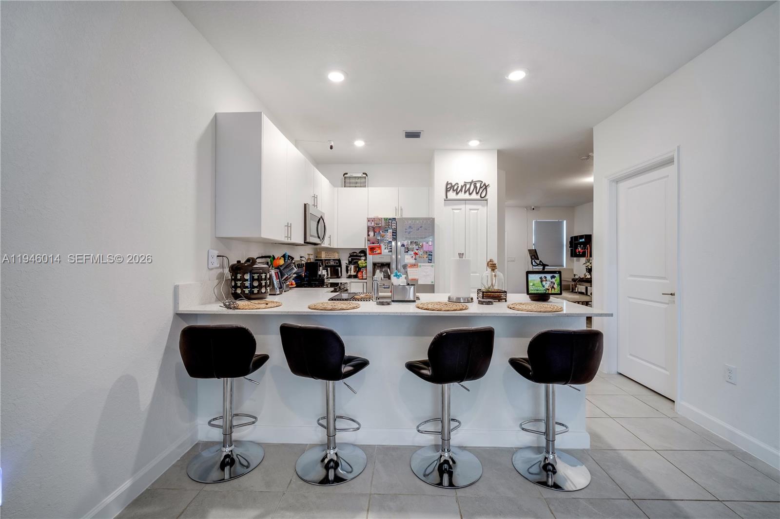 28574 Southwest 134th Court, Unit 28574 Homestead, FL 33033 - Photo 5 of 29 a kitchen with a sink a counter and chairs