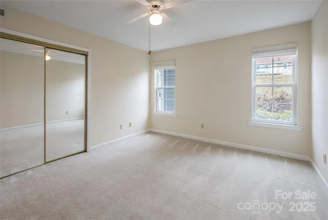 an empty room with windows and ceiling fan
