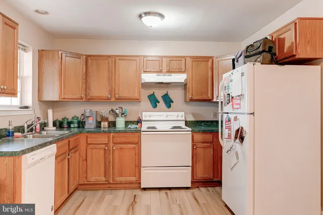 a kitchen with a refrigerator a stove a sink dishwasher and wooden cabinets with wooden floor
