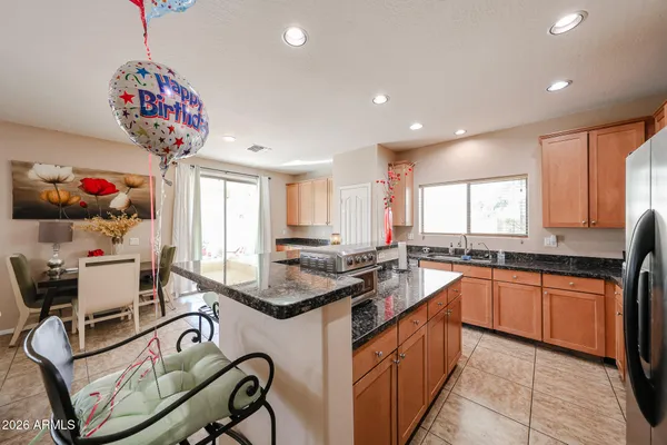 a kitchen with stainless steel appliances kitchen island granite countertop a refrigerator a stove a microwave oven a dining table and chairs with wooden floor
