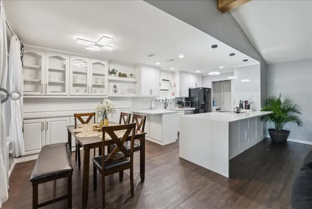 a kitchen with a dining table chairs wooden floor appliances and cabinets