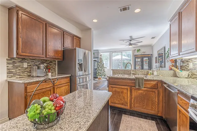a kitchen with stainless steel appliances granite countertop sink stove refrigerator and cabinets