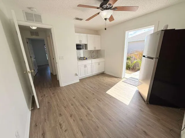 a view of a kitchen with wooden floor and electronic appliances