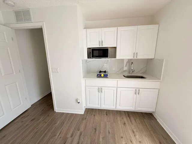 a kitchen with cabinets and wooden floor